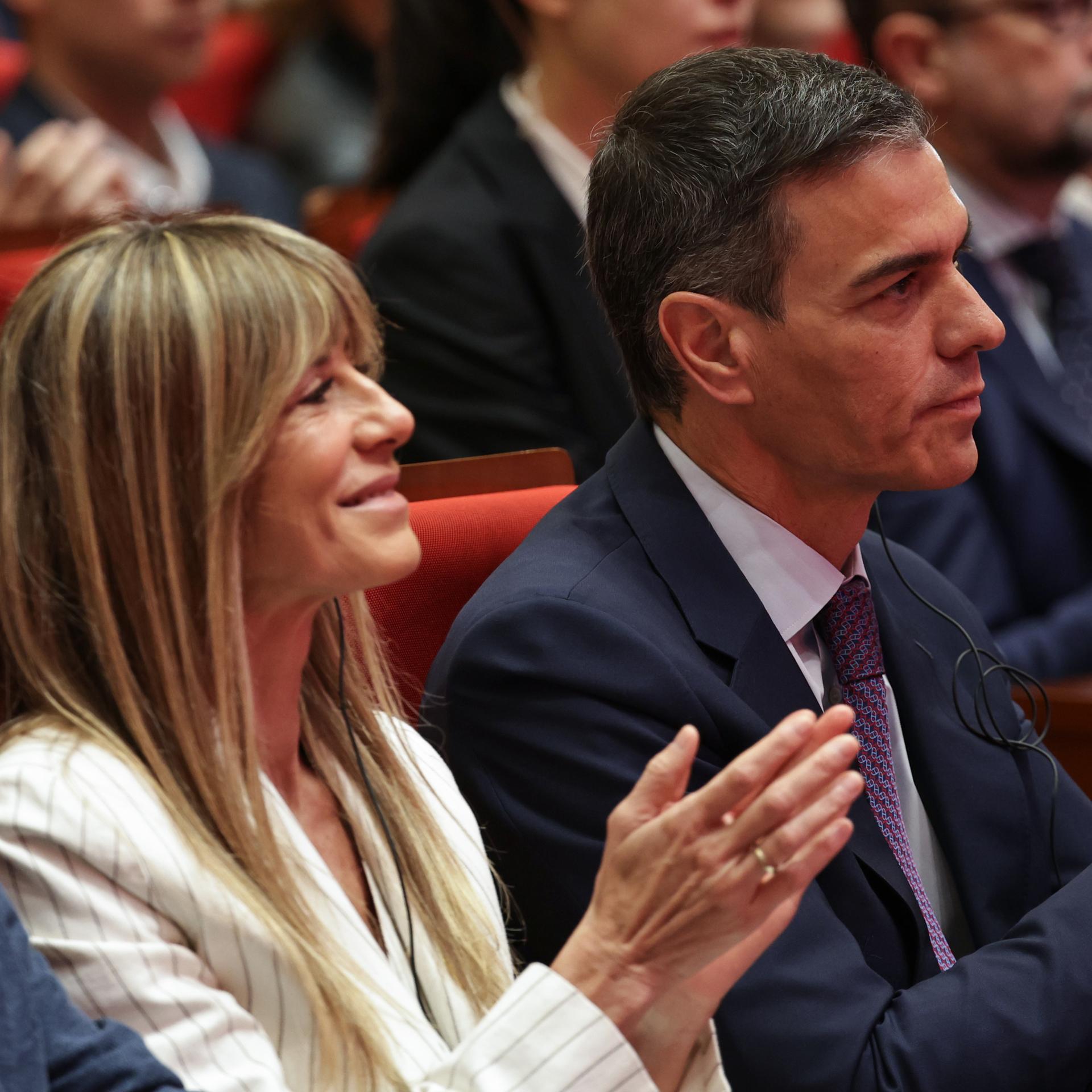 Der spanische Ministerpräsident Pedro Sánchez und seine Frau Begona Gómez sitzen nebeneinander und applaudieren.