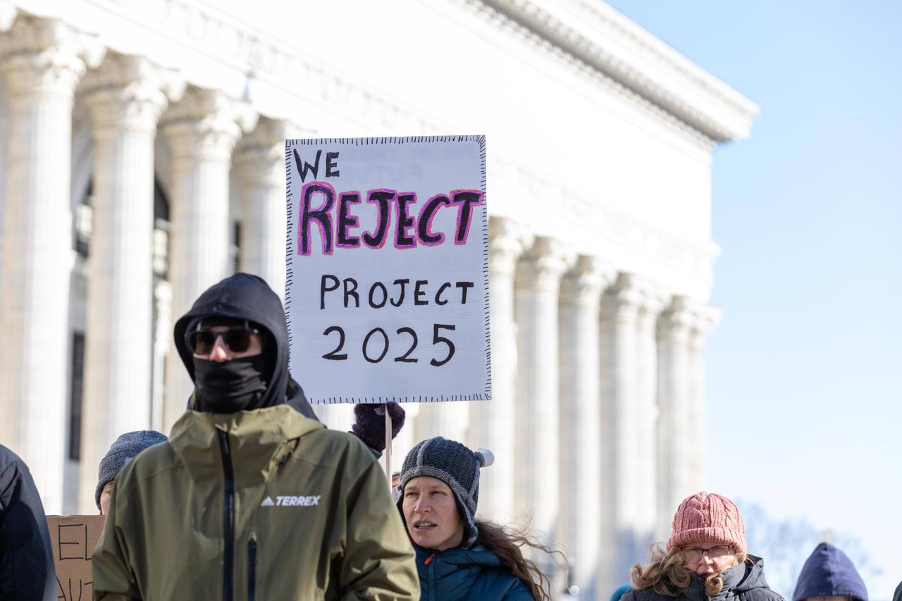 Eine Frau auf einer Demonstration hält ein Schild hoch mit der Aufschrift "Reject Project 2025", übersetzt: "Lehnt Project 2025 ab." 