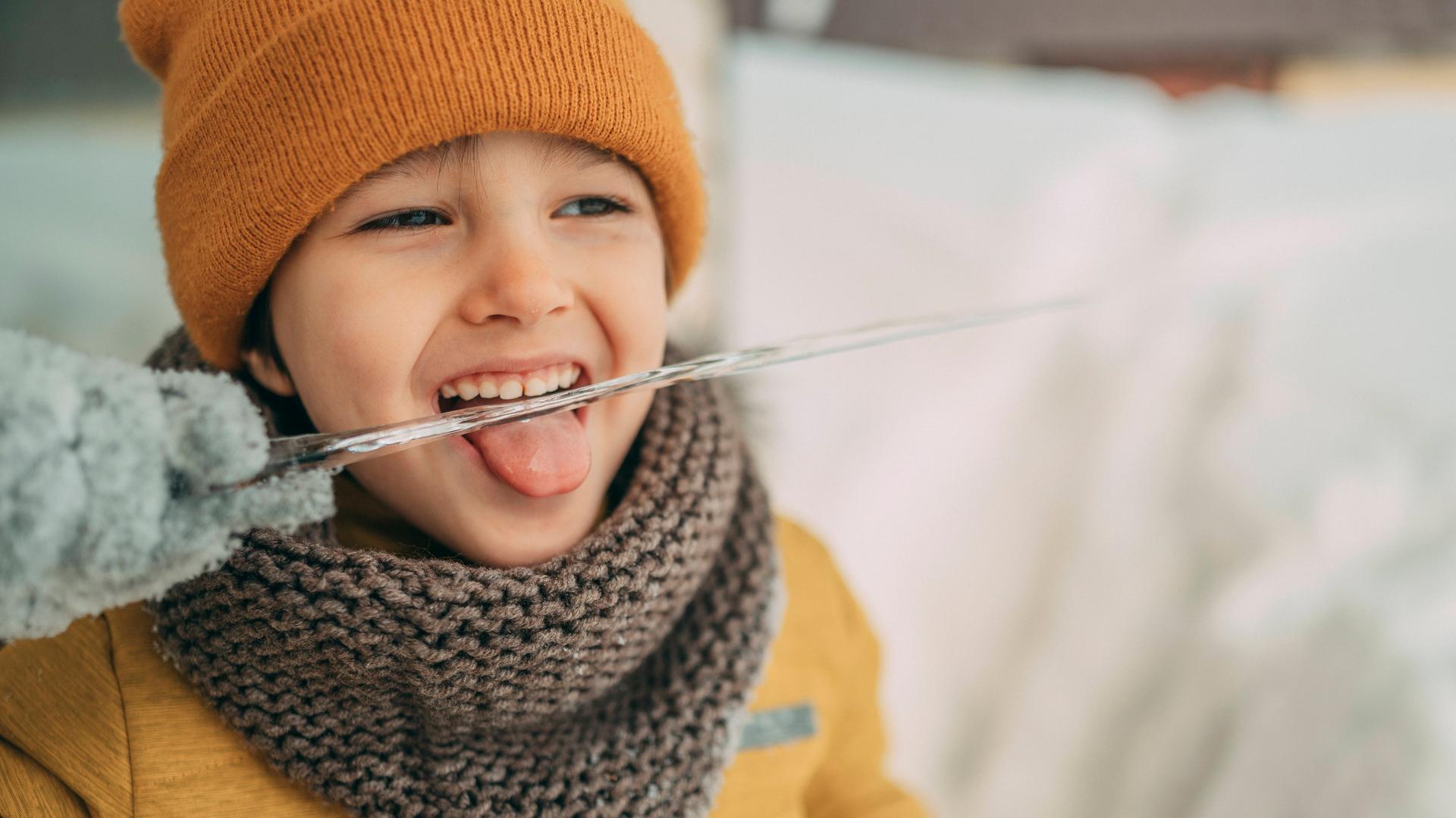 Junge im Winter leckt  an einem Eiszapfen