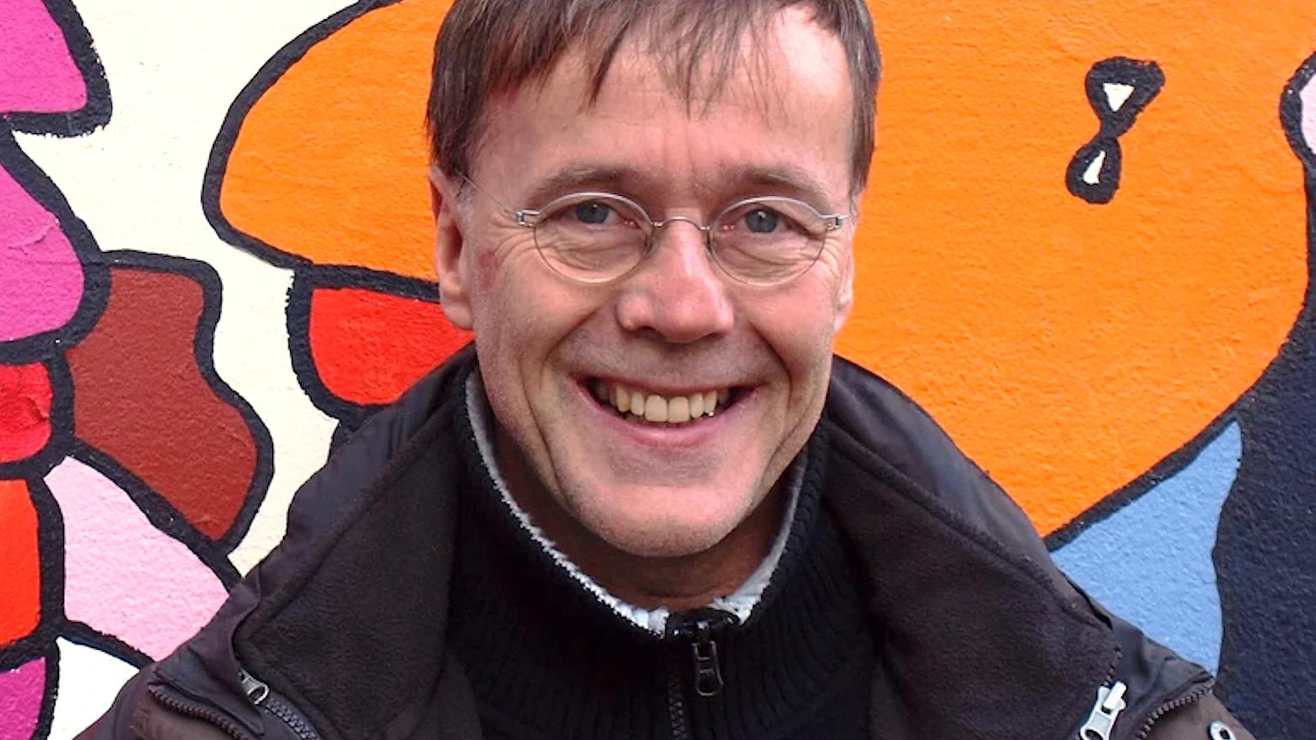 Porträt von Christoph Antweiler. Mittelalter weißer Mann vor einer Wand mit Graffiti Kunst. Porträt von Christoph Antweiler. Mittelalter weißer Mann vor einer Wand mit Graffiti Kunst.
