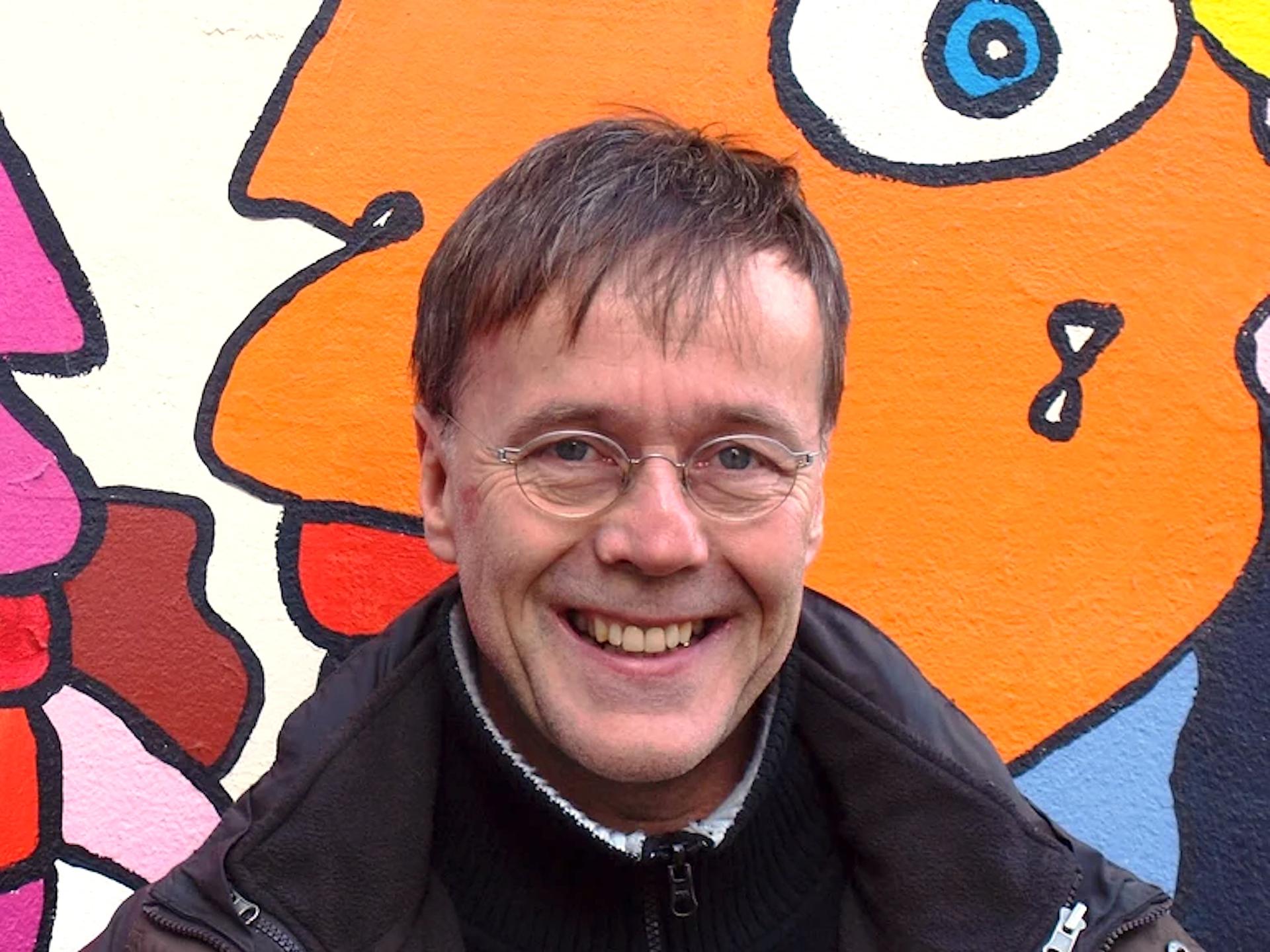 Porträt von Christoph Antweiler. Mittelalter weißer Mann vor einer Wand mit Graffiti Kunst.