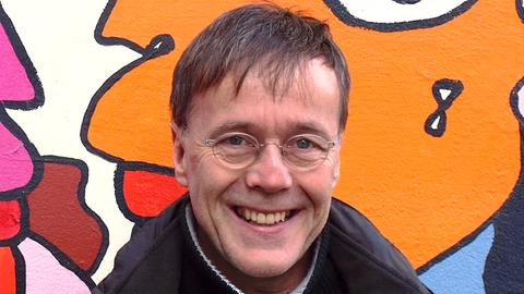 Porträt von Christoph Antweiler. Mittelalter weißer Mann vor einer Wand mit Graffiti Kunst.