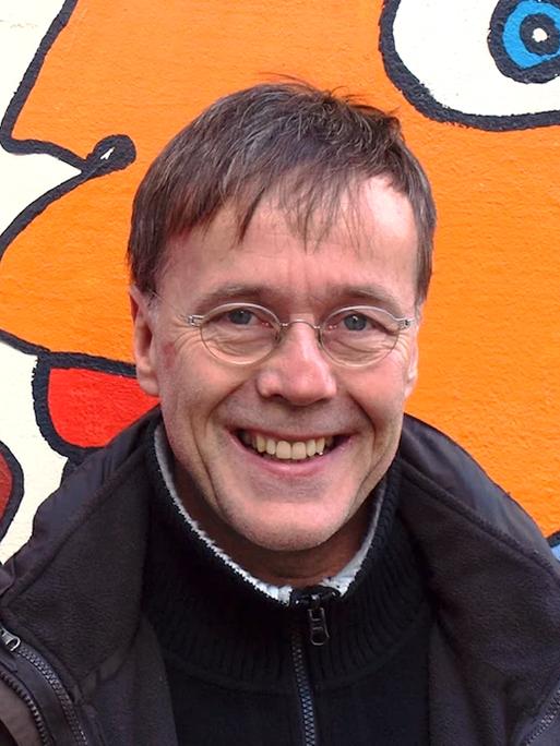 Porträt von Christoph Antweiler. Mittelalter weißer Mann vor einer Wand mit Graffiti Kunst.