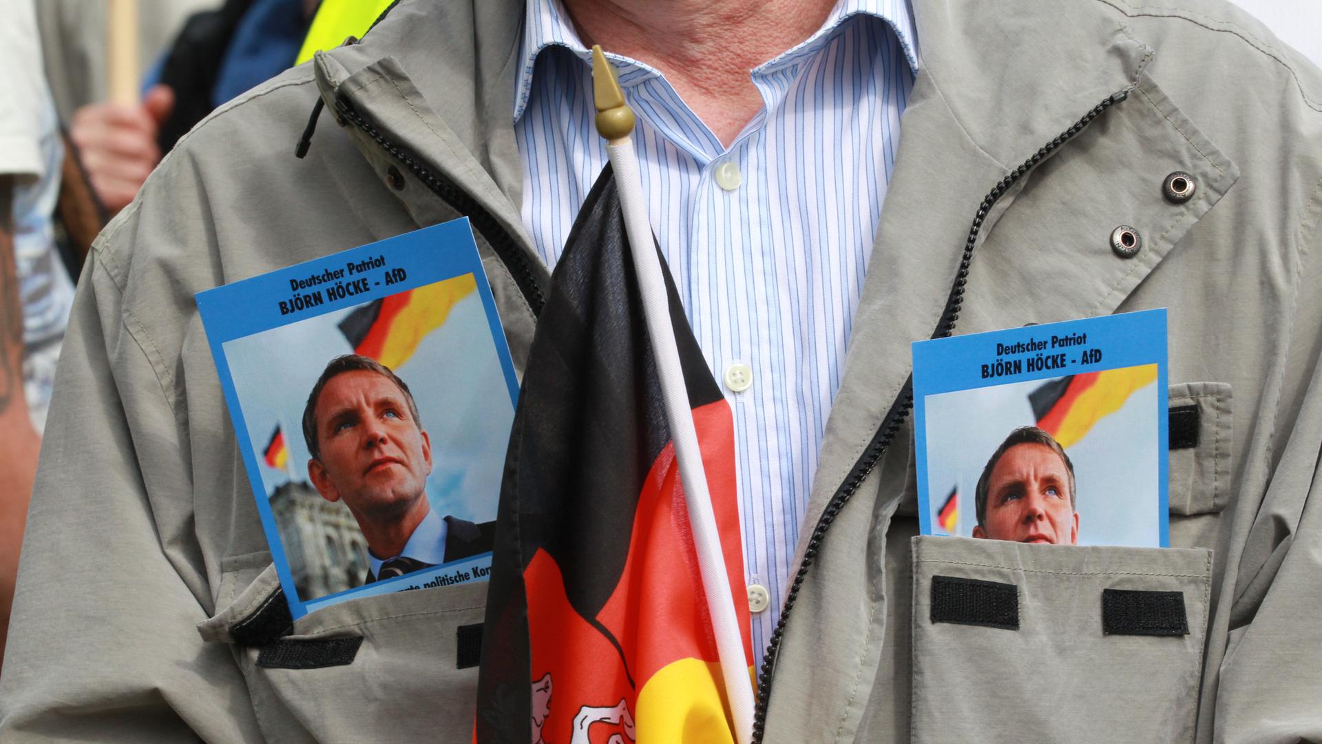 Ein Anhänger der AfD demonstriert mit zwei Fotos von Björn Höcke, Fraktionsvorsitzender der AfD im Landtag und einer Deutschlandfahne in der Innenstadt.