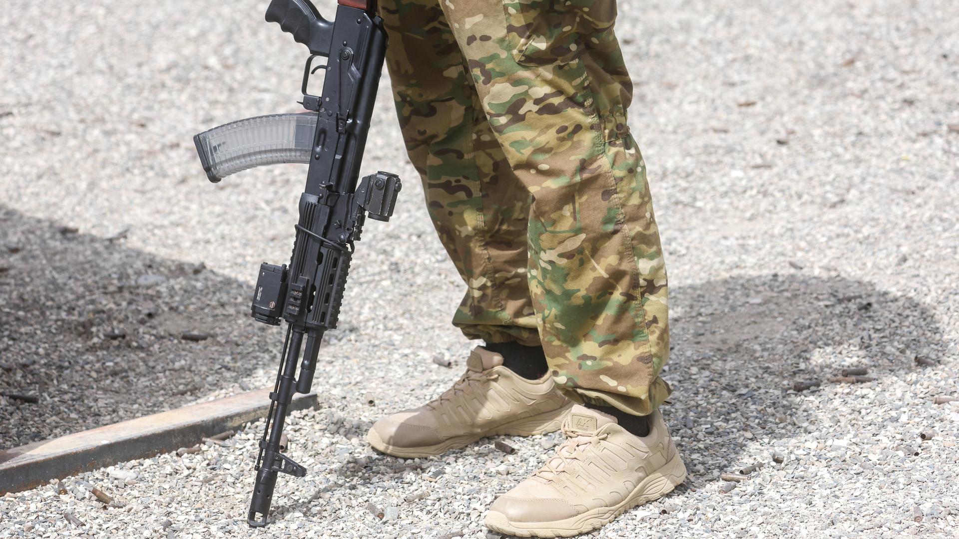 Das Bild zeigt nur die Beine des Soldaten in Tarnhosen. Er lehnt sein gewehr auf den Boden. Das Bild zeigt nur die Beine des Soldaten in Tarnhosen. Er lehnt sein gewehr auf den Boden.