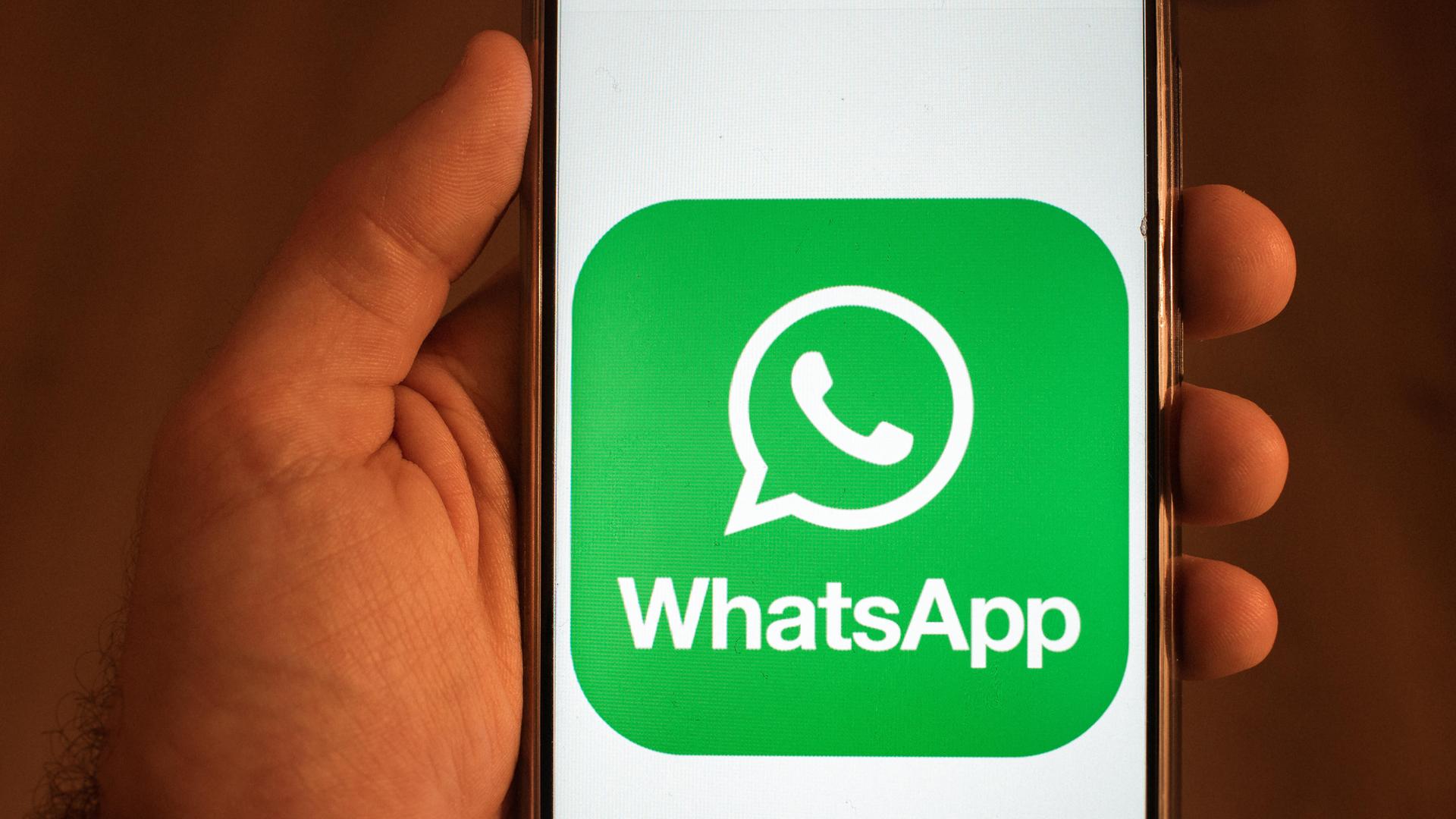 Eine Hand hält ein Handy. Darauf ist das Logo der App "WhatsApp" zu sehen. Eine Hand hält ein Handy. Darauf ist das Logo der App "WhatsApp" zu sehen.