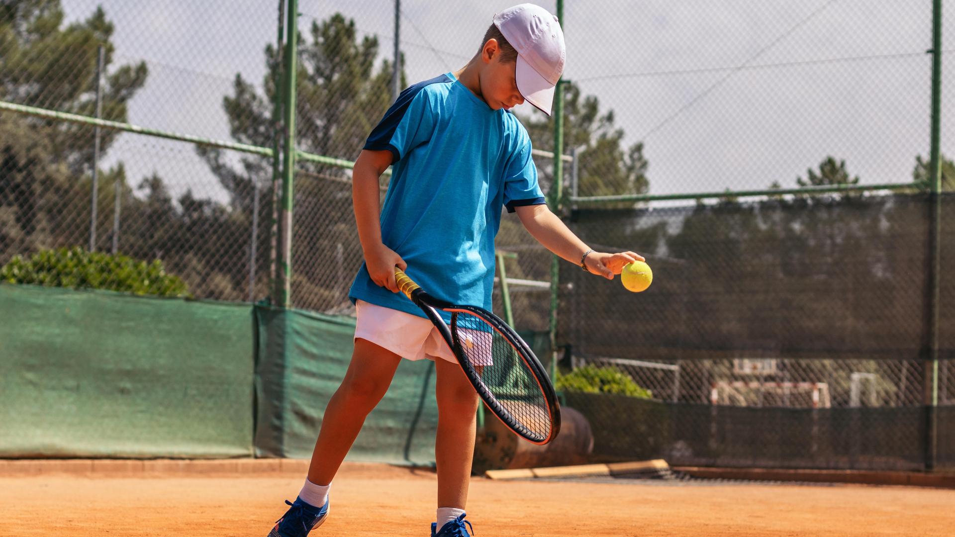 Junge spielt Tennis auf dem Tennisplatz