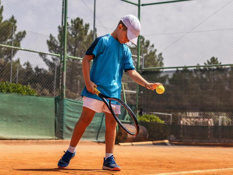 Junge spielt Tennis auf dem Tennisplatz