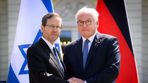 Bundespräsident Frank-Walter Steinmeier (r) und Izchak Herzog, Präsident von Israel, geben sich am Ende einer Pressekonferenz nach ihrem Gespräch im Schloss Bellevue die Hand. Im Hintergrund die Fahnen beider Staaten. 