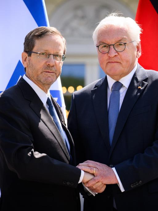 Bundespräsident Frank-Walter Steinmeier (r) und Izchak Herzog, Präsident von Israel, geben sich am Ende einer Pressekonferenz nach ihrem Gespräch im Schloss Bellevue die Hand. Im Hintergrund die Fahnen beider Staaten. 