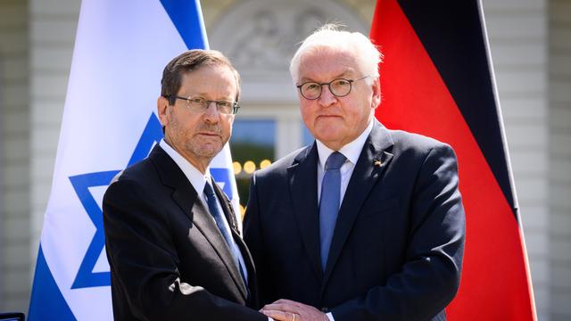 Bundespräsident Frank-Walter Steinmeier (r) und Izchak Herzog, Präsident von Israel, geben sich am Ende einer Pressekonferenz nach ihrem Gespräch im Schloss Bellevue die Hand. Im Hintergrund die Fahnen beider Staaten. 