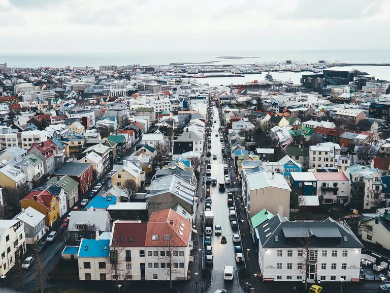 Vogelperspektive von Reykjavik mit zahlreichen Gebäuden und der Küstenlinie im Hintergrund.