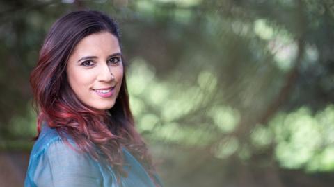 Eine Frau schaut über die rechte Schulter in die Kamera. 