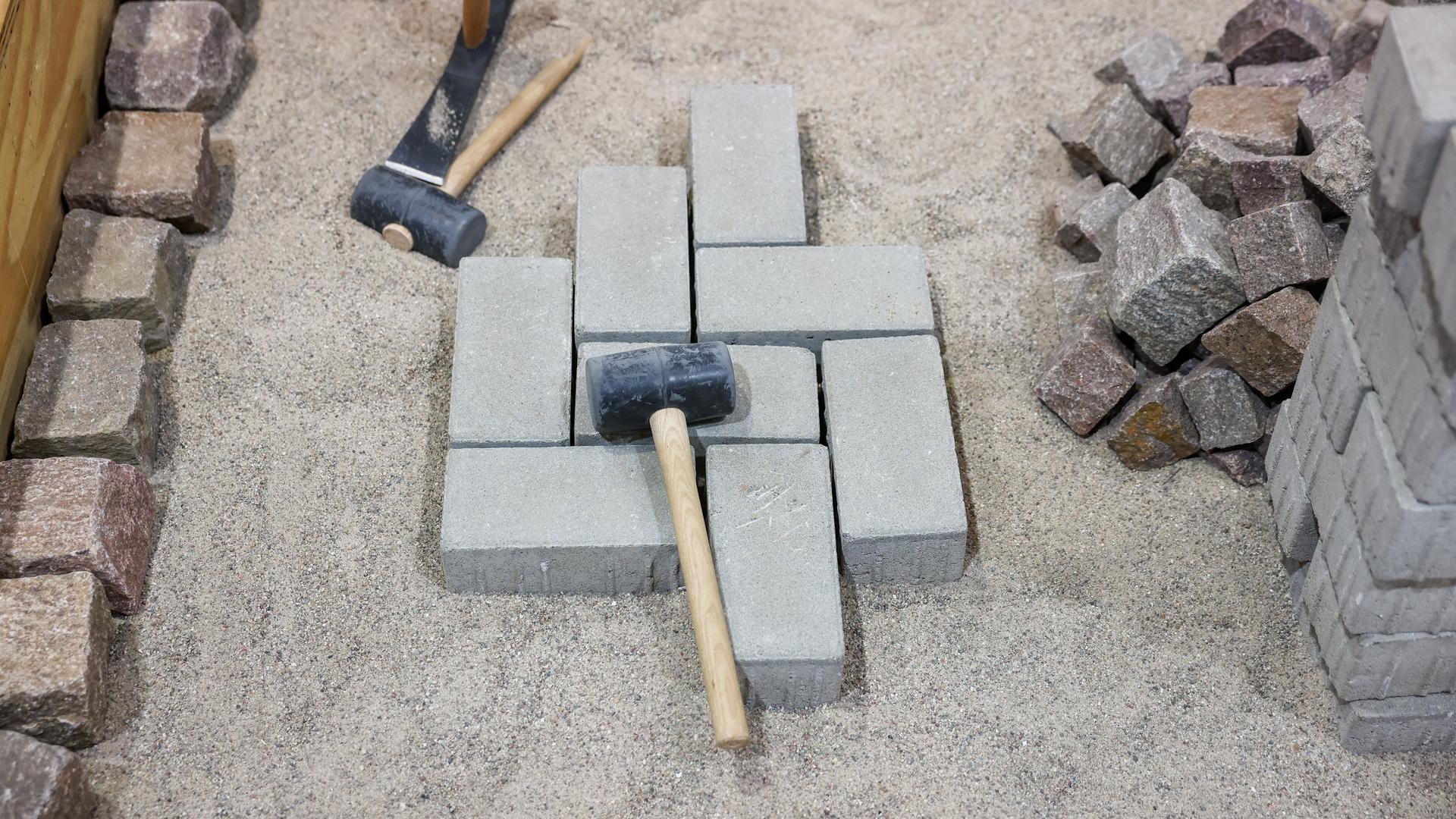 Hammer und Pflastersteine liegen auf einer Baustelle auf einer Kiesgrube.