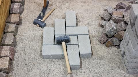 Hammer und Pflastersteine liegen auf einer Baustelle auf einer Kiesgrube.