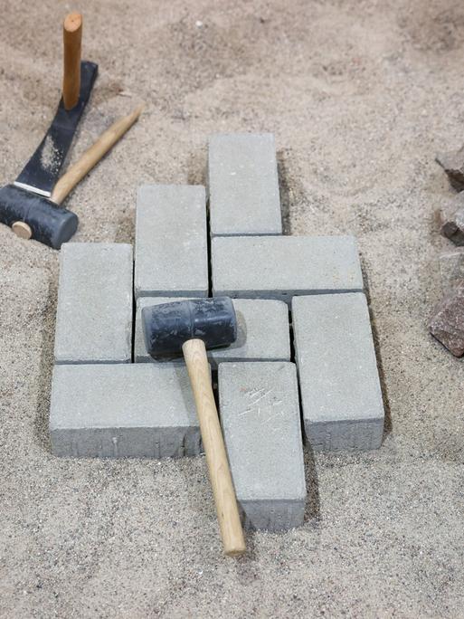 Hammer und Pflastersteine liegen auf einer Baustelle auf einer Kiesgrube.