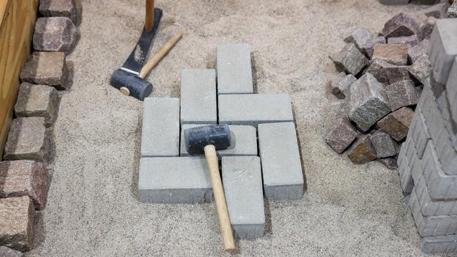 Hammer und Pflastersteine liegen auf einer Baustelle auf einer Kiesgrube.