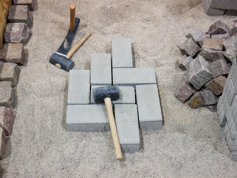 Hammer und Pflastersteine liegen auf einer Baustelle auf einer Kiesgrube.