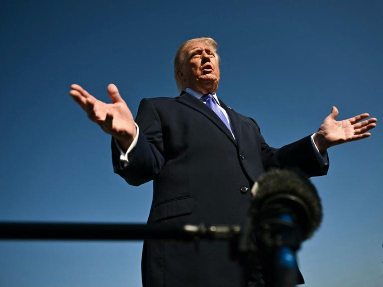 Starke Untersicht auf Donald Trump, der gestikulierend in ein Mikrofon spricht.