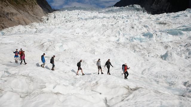 Touristen laufen über einen riesigen Gletscher.