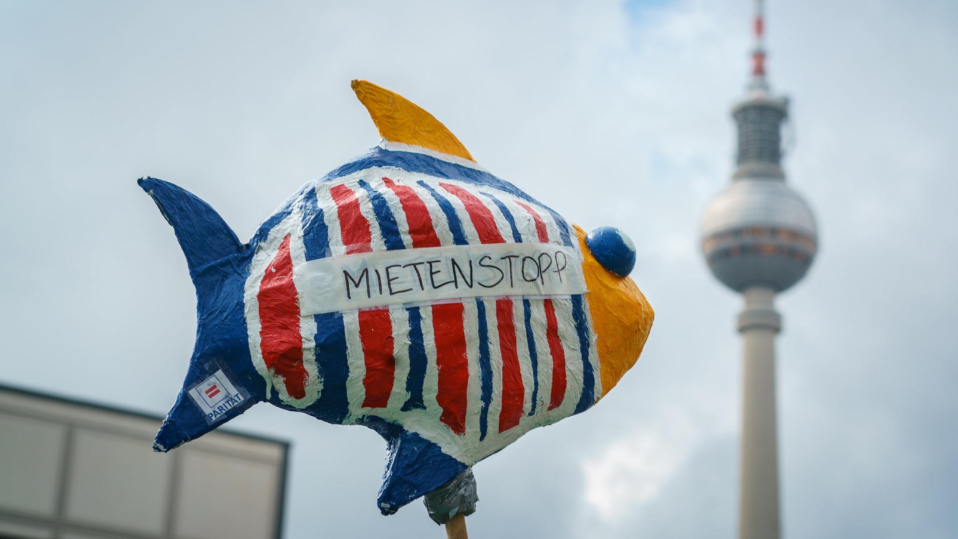 Bei einer Demonstration in Berlin sind ein Fisch mit der Aufschrift "Mietenstopp" und im Hintergrund der Berliner Fernsehturm zu sehen.