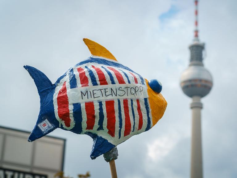 Bei einer Demonstration in Berlin sind ein Fisch mit der Aufschrift "Mietenstopp" und im Hintergrund der Berliner Fernsehturm zu sehen.