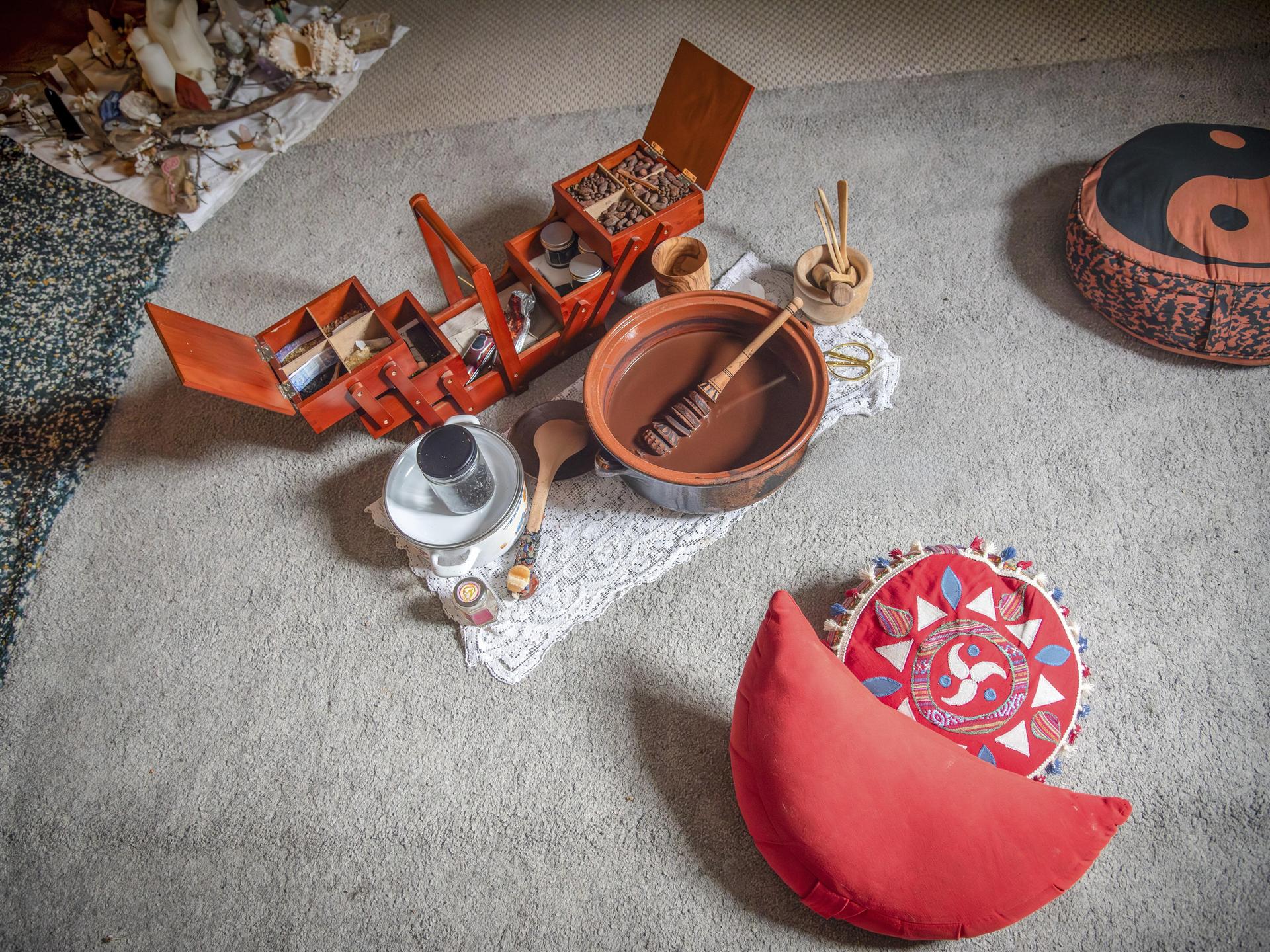 Meditationsecke mit roten Sitzkissen und einem Set aus Holzboxen, Schalen und Utensilien auf einem Teppich