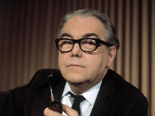 Der Schweizer Autor Max Frisch hält eine Pfeife in der Hand und schaut in die Kamera