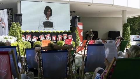 Menschen liegen in Liegestühlen vor einer Leinwand, aber der eine Lesung beim Ingeborg-Bachmann-Preis übertragen wird.