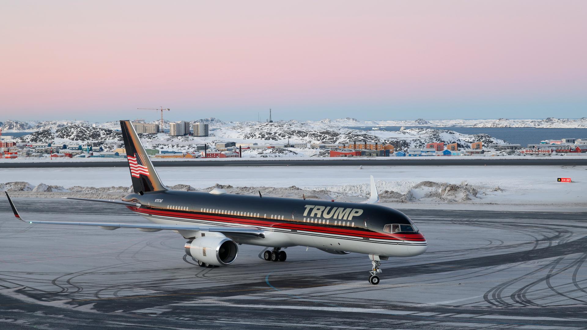 Ein Flugzeug mit dem Schriftzug "Trump" landet auf dem Flughafen von Nuuk. Im Hintergrund sind die verschneite Stadt und der Fjord zu sehen.