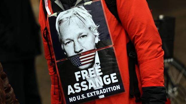Ein Demonstrant hat sich ein Foto von Julian Assange umgehängt