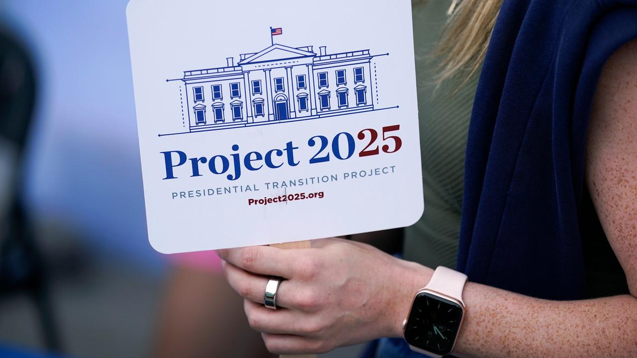 Eine Person hält ein Schild mit der Aufschrift "Project 2025" in der Hand. Darauf ist außerdem eine Zeichnung des Weißen Hauses zu sehen.