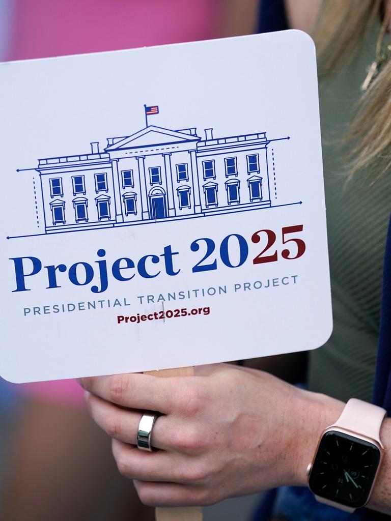 Eine Person hält ein Schild mit der Aufschrift "Project 2025" in der Hand. Darauf ist außerdem eine Zeichnung des Weißen Hauses zu sehen.