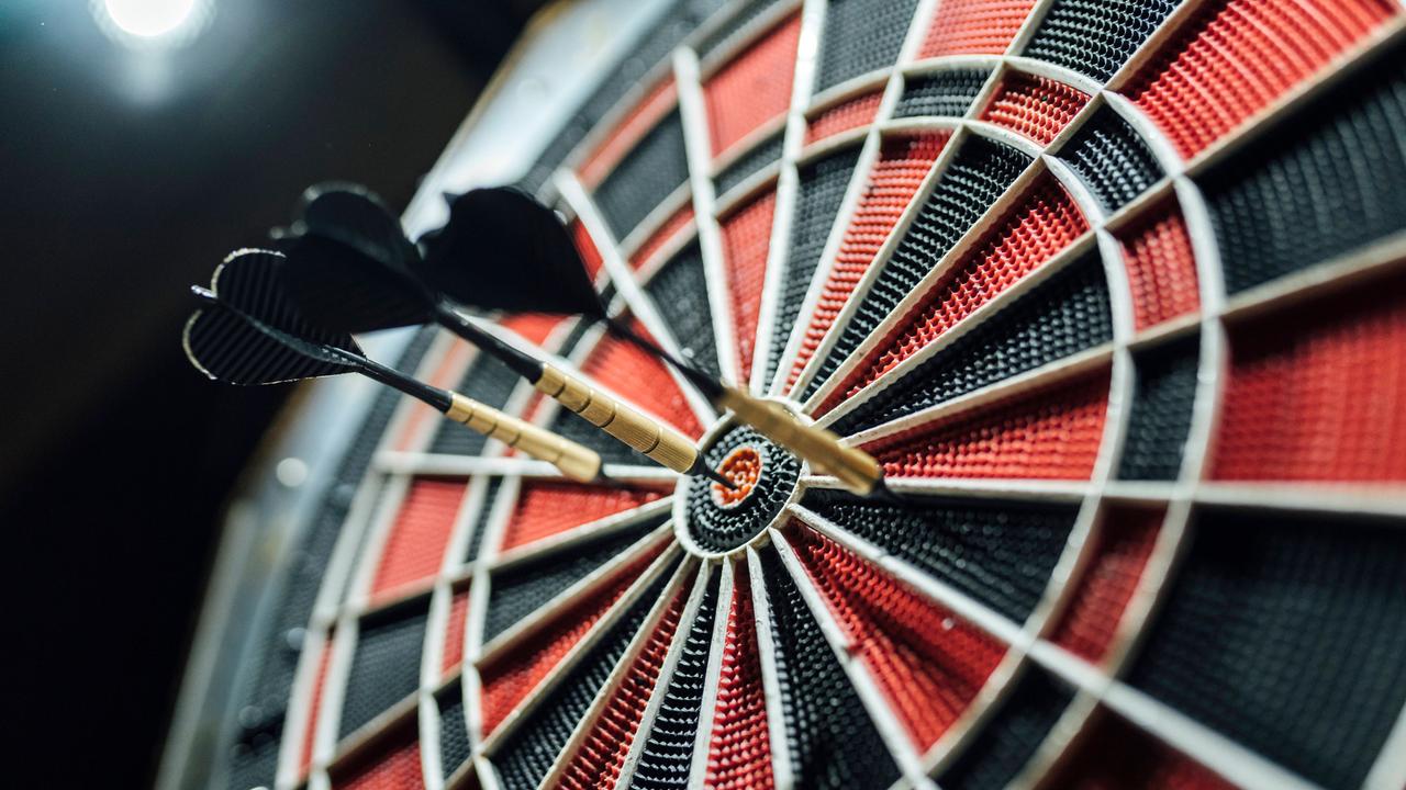 Drei Pfeile stecken in einer Dartscheibe.