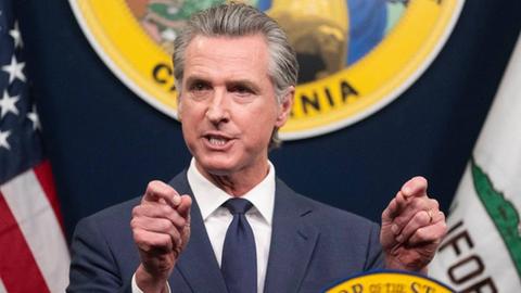 Der Gouverneur von Kalifornien, Gavin Newsom, spricht an einem Rednerpult.