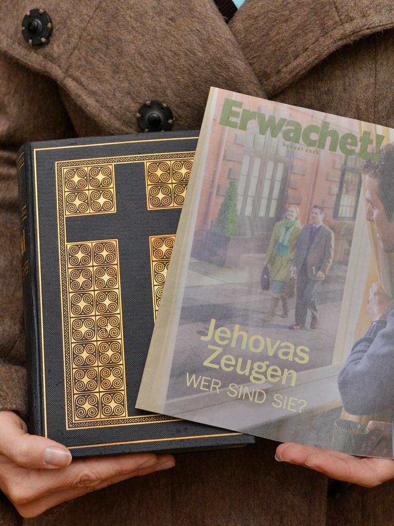 Ein Zeuge Jehovas mit Bibel und Broschüre "Erwachet" in der Hand.