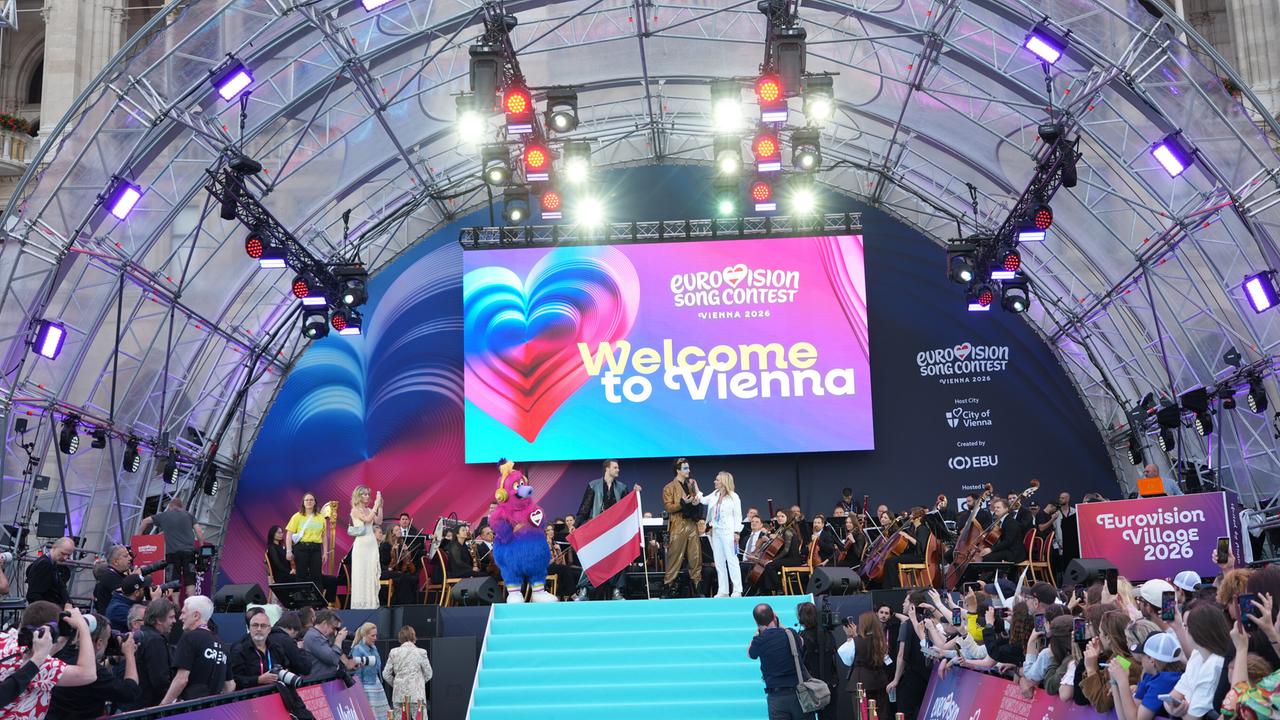 Die Eröffnungsfeier der ESC-Woche in Wien - Moderatoren und Sänger stehen auf der Bühne. Unten sind entlang eines Laufstegs Publikum und Kamerateams zu sehen.