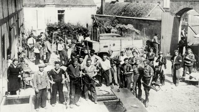 Nach der alliierten Invasion in der Normandie im Sommer 1944 wartet eine Gruppe von Partisanen mit Gewehren auf einem Gehöft (bei Chateaudun) auf den Einsatzbefehl gegen deutsche Stellungen.