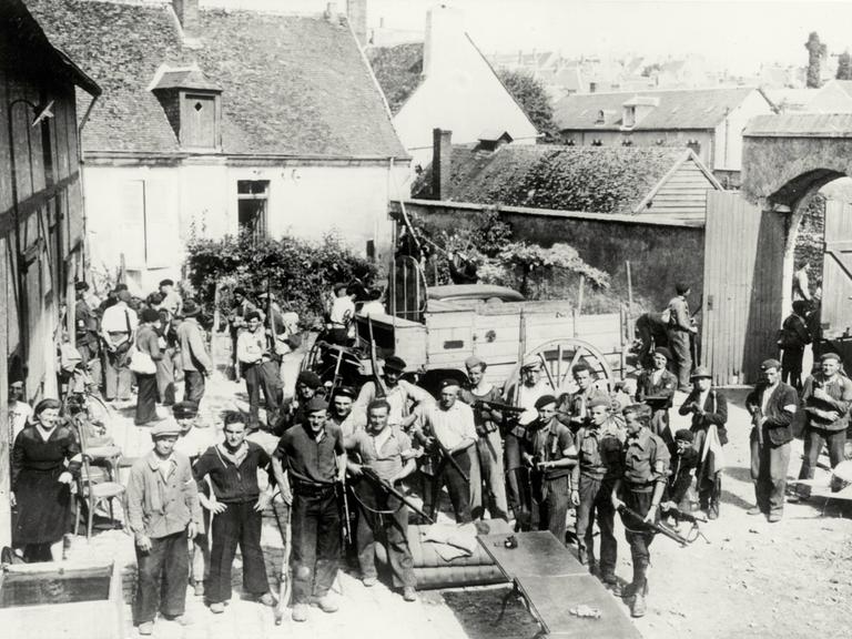 Nach der alliierten Invasion in der Normandie im Sommer 1944 wartet eine Gruppe von Partisanen mit Gewehren auf einem Gehöft (bei Chateaudun) auf den Einsatzbefehl gegen deutsche Stellungen.