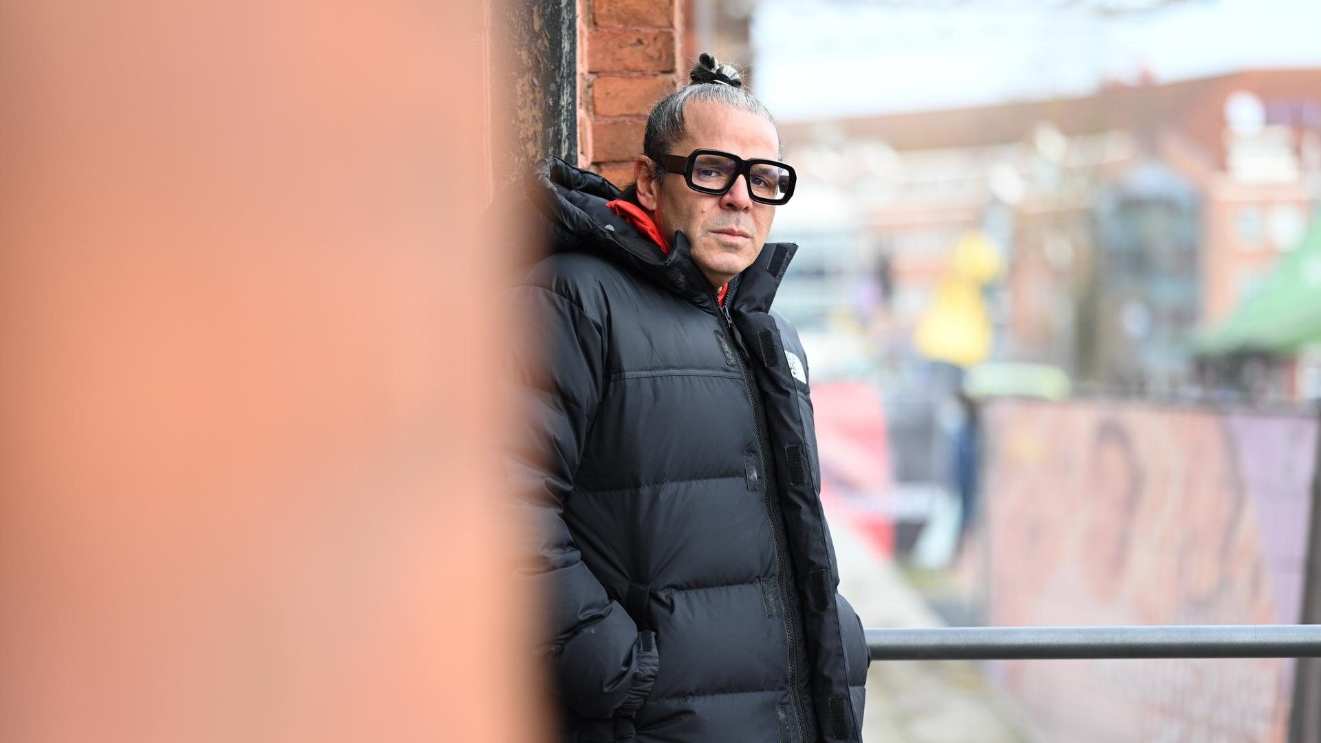 Luigi Toscano lehnt an einer Wand und schaut ernst in die Kamera.