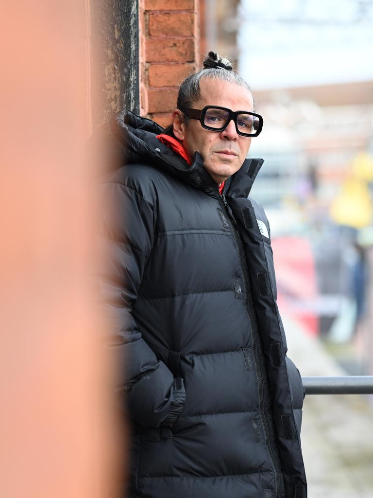 Luigi Toscano lehnt an einer Wand und schaut ernst in die Kamera.