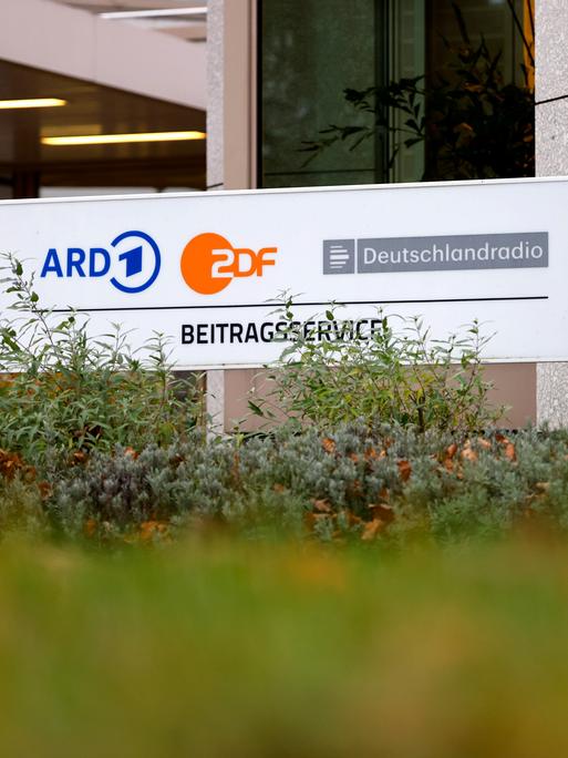 Auf einem Schild sind die Logos von ARD, ZDF und Deutschlandradio zu sehen.