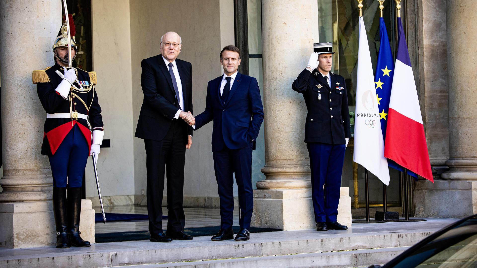 Frankreichs Präsident Emmanuel Macron schüttelt die Hand des geschäftsführenden Ministerpräsidenten des Libanons, Nadschib Mikati, daneben stehen zwei Militärangehörige