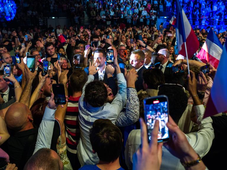 Bei einem Treffen des Rassemblement National in Narbonne umringen zahlreiche junge Menschen Jordan Bardella und fotografieren und filmen ihn mit ihren Handys. 