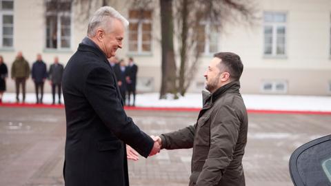 Nauseda und Selenskyj stehen sich gegenüber und schütteln sich die Hände.