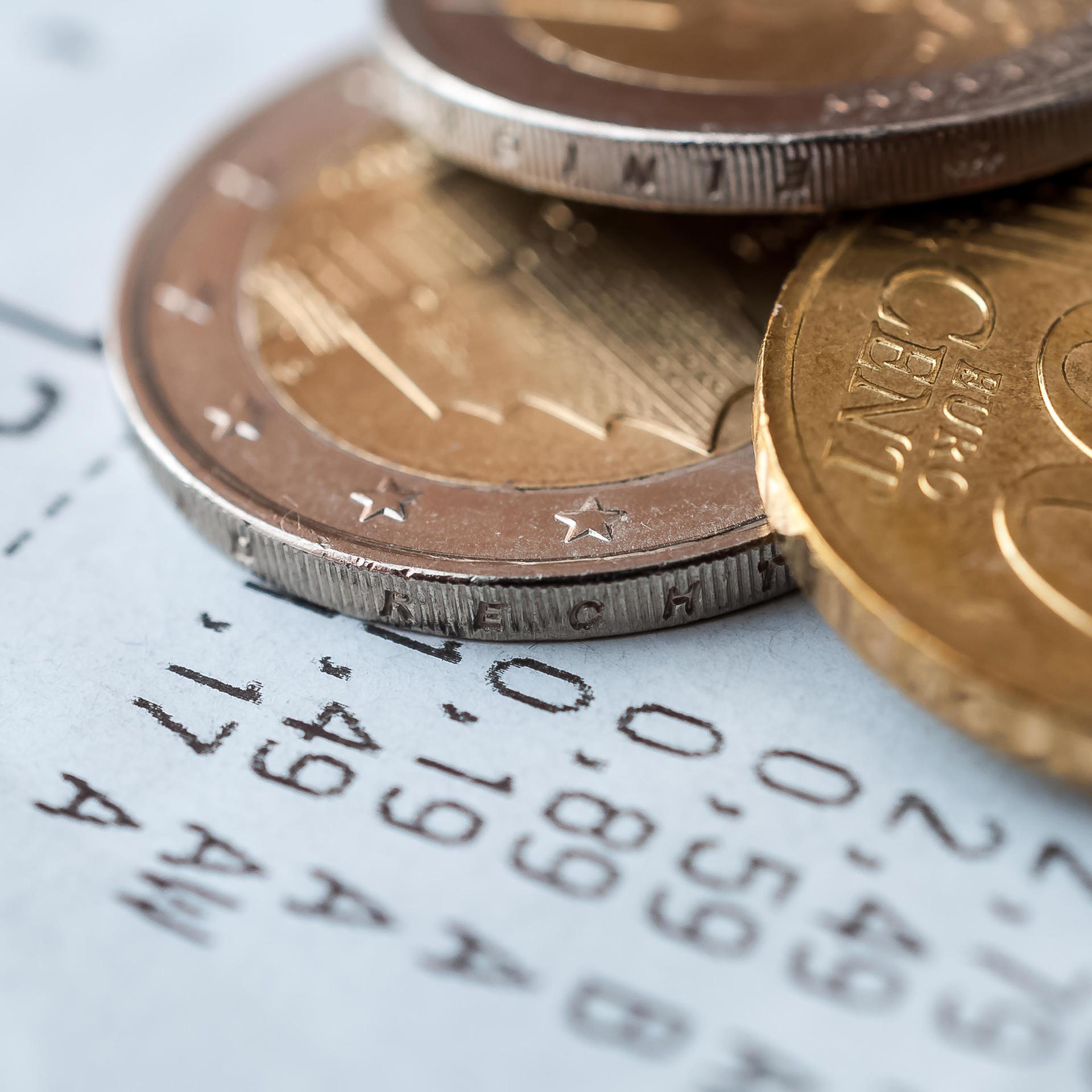 Auf einem Kassenzettel liegen verschiedene Euro-Münzen.