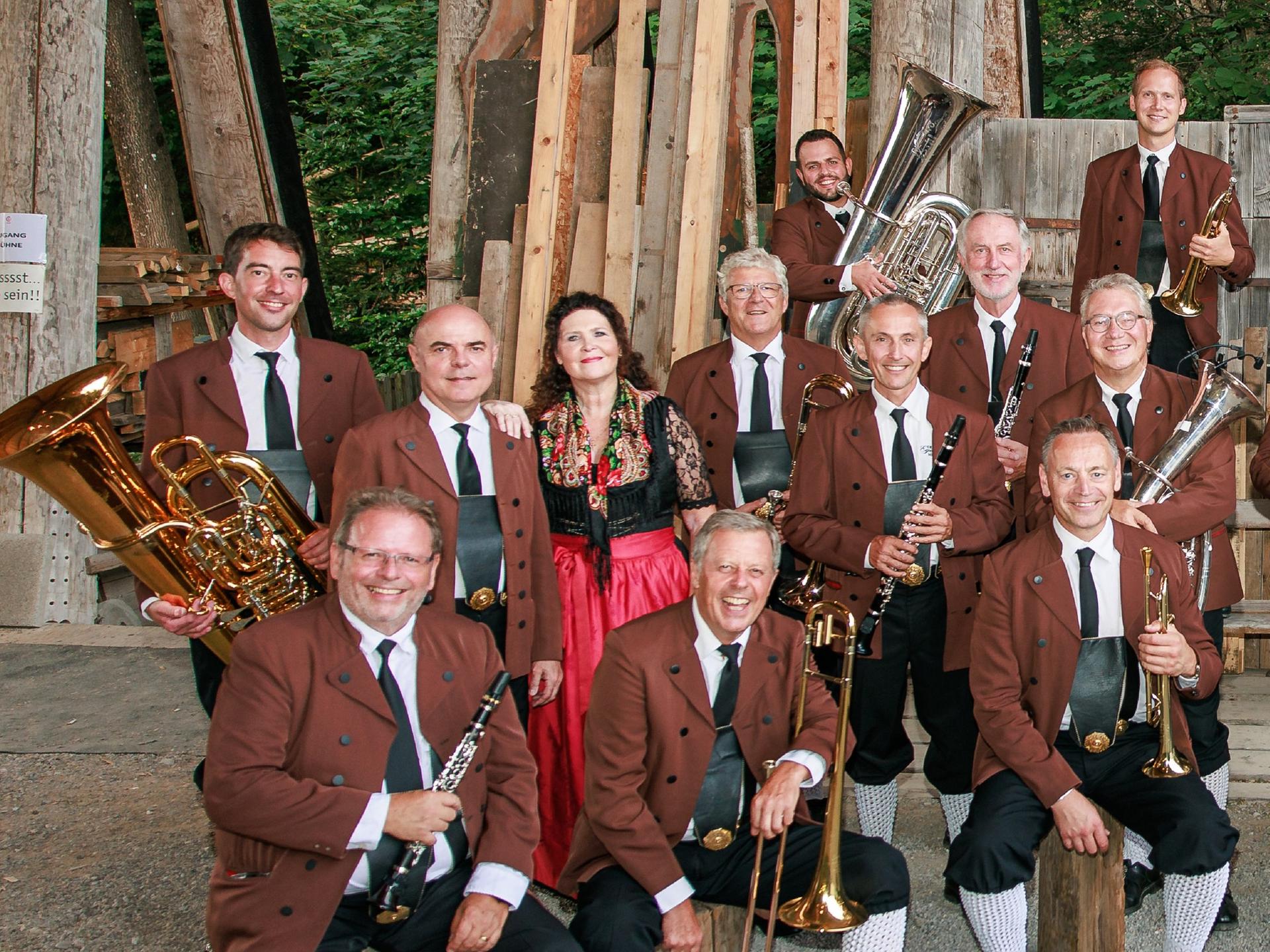 Ein Teil der Musiker sitzt und steht lachend vor der Kamera mit ihren Instrumenten in den Händen.