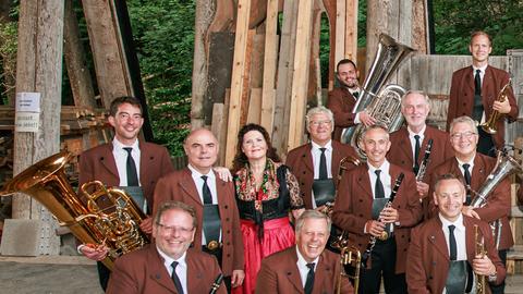 Ein Teil der Musiker sitzt und steht lachend vor der Kamera mit ihren Instrumenten in den Händen.
