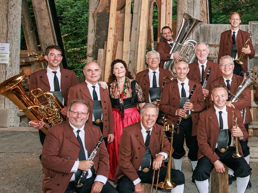 Ein Teil der Musiker sitzt und steht lachend vor der Kamera mit ihren Instrumenten in den Händen.