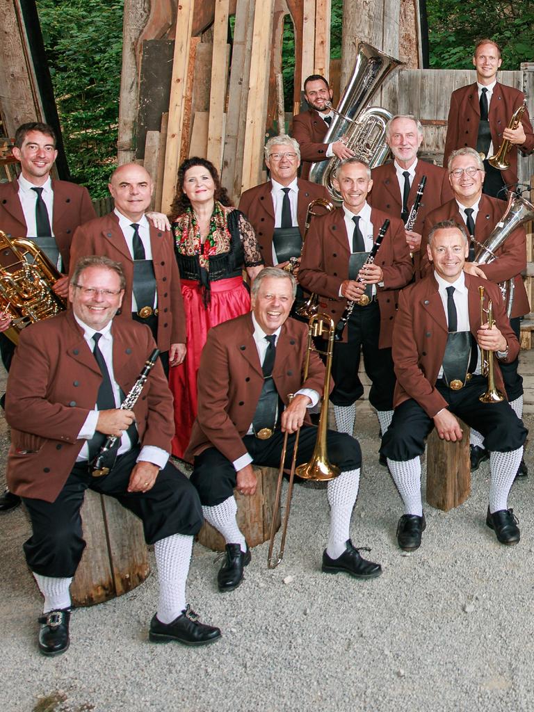 Ein Teil der Musiker sitzt und steht lachend vor der Kamera mit ihren Instrumenten in den Händen.
